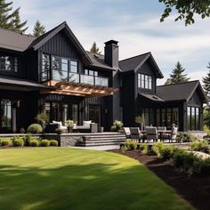 a large black house with lots of windows on it's sides and stairs leading up to the front door