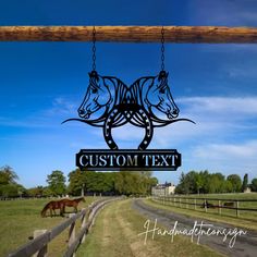 a horse logo hanging from the side of a wooden fence in front of a field