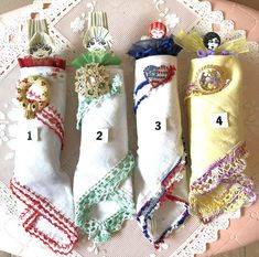 four folded towels are sitting on a lace doily with numbers and ribbons around them