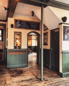 the inside of a restaurant with wood floors and green trim on the walls, along with chalkboard menus