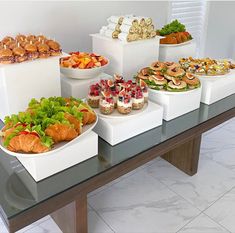 a table topped with lots of different types of sandwiches and pastries on trays