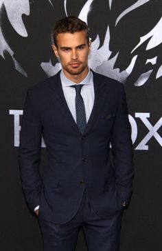 a man in a suit and tie standing next to a wall with the wolf logo on it