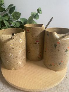 three ceramic vases sitting on top of a wooden stand next to a planter