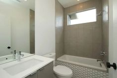 a white toilet sitting next to a bath tub in a bathroom under a window with a skylight