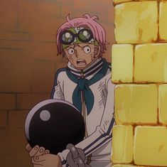 a man with pink hair and goggles holding a ball in front of a brick wall