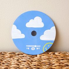 a blue and white clock sitting on top of a wicker basket next to a wall