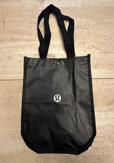 This Lululemon tote bag is a stylish and practical choice for your shopping needs. With a sleek black color and white logo, it's perfect for everyday use. Measuring 11 inches in length, 4 inches in width and 9 inches in height, this small tote is great for carrying your essentials. It features a solid pattern and is made of high-quality materials to ensure durability. The bag is an original Lululemon product and comes in a pack of one. It's suitable for a variety of occasions and will complement any outfit. Ideal for those who prioritize functionality and style, this tote bag is a must-have. Lululemon Tote Bag, Lululemon Bag, Popular Things, Black White Logo, Lululemon Bags, Bags Tote, Reusable Shopping Bags, Small Tote, Shopping Tote Bag