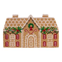 a gingerbread house door mat with holly wreaths and bells on the front is shown