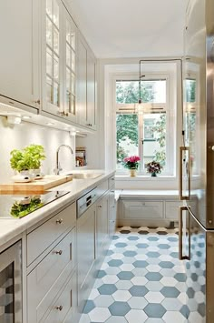 a kitchen with white cabinets and tiled flooring next to a window in the wall