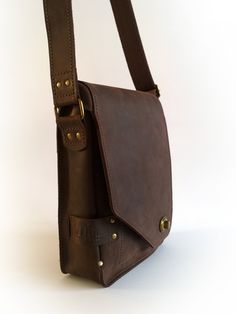 a brown leather shoulder bag sitting on top of a white table