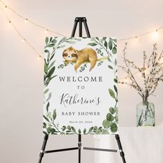 a welcome sign with a baby sloth on it and greenery around the frame