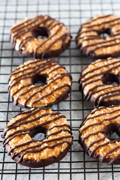 chocolate covered donuts sitting on top of a cooling rack