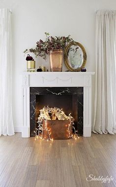 a white fireplace with christmas lights in front of it and a potted plant on top