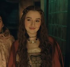 two young women dressed in period costumes standing next to each other, one wearing a tiara