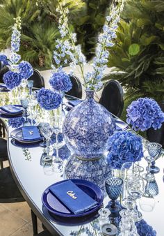 the table is set with blue and white plates, silverware, and vases