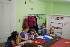 a group of children sitting at a table with paper work on it in front of them