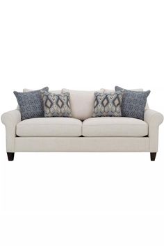 a white couch with pillows on top of it and two blue throw pillows in the back