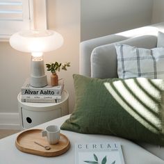 a coffee cup on a tray next to some books and a lamp in a living room