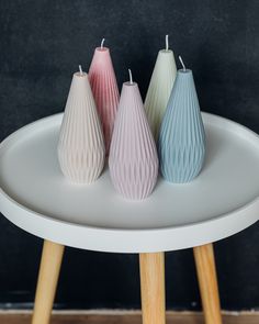 three small vases sitting on top of a white table next to each other in front of a black wall