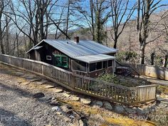 a house in the woods with a metal roof and wooden railings on it's side