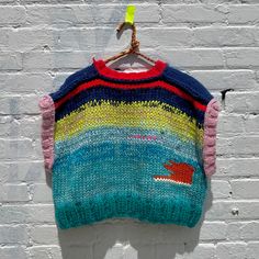 a colorful sweater hanging on a brick wall