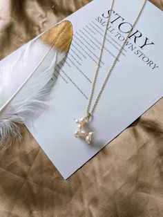 a book with a feather on it next to a necklace that says story stationery