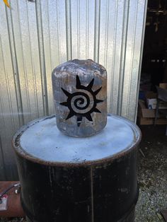 a black and white object sitting on top of a metal barrel