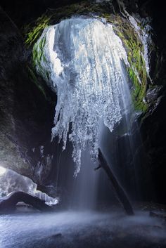 an ice covered waterfall in the middle of a cave