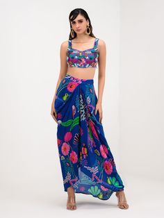 A three-piece Marine Blue Printed Dhoti Skirt Set Paired With Bralette and Cape from the Juhi Bengani collection – Festive 2023. This gorgeous marine blue printed dhoti skirt is paired with a heavy embroidered bralette blouse. The bright and vibrant prints with bird and floral work, heavy embroidery of beads, and thread sequence work enhance this pure crepe dhoti skirt set. This outfit is completed with a marine blue printed cape with embroidered lace border. Blue Pre-draped Saree With Floral Print, Bollywood Style Blue Saree For Summer, Blue Bollywood Saree For Summer, Digital Print Saree Set For Summer, Blue Bohemian Lehenga For Party, Blue Summer Festive Saree, Summer Festive Blue Saree, Traditional Summer Saree With Digital Print, Traditional Summer Digital Print Saree