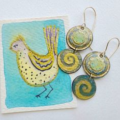 Unique funky artisan handpainted watercolor paper earrings on handmade gold filled earwires and a special original watercolor bird painting. The top component has a few layers of circles glued together with hand painted detal and gilded with gold paint. The lower circle has a wave design in a teal blue and gold. The reverse side of both pieces have printed paper that I glued on. I sanded the edges and sealed them and the entire piece with acrylic sealer and gave them a painted edge. See all 10 p Watercolor Earrings, Watercolor Jewelry, Blue Green Gold, Paper Earrings, Bird Painting, Homemade Jewelry, Gold Filled Earrings, Wave Design, Watercolor Bird