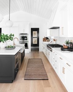 the kitchen is clean and ready for us to use it's white cabinets, wood floors, and black appliances