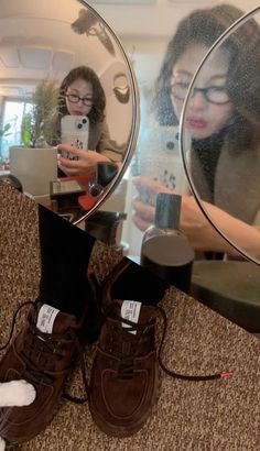 a woman is looking at her cell phone in front of a mirror while another person takes a selfie