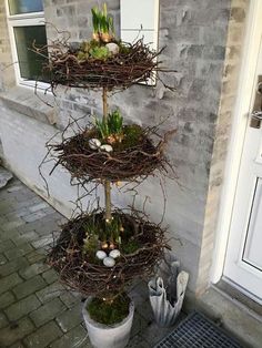 three tiered bird nest planter with eggs in it on the side of a building