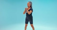 a woman is standing in front of a blue background with her hands on her hips