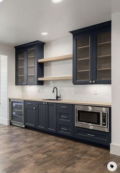 an empty kitchen with blue cabinets and wood floors