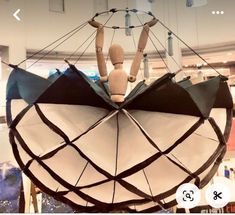 a wooden mannequin sitting on top of an upside down umbrella in a store