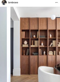 a living room filled with lots of wooden bookshelves next to a white chair