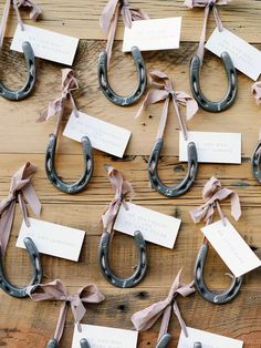 several metal horseshoes with tags attached to them sitting on a wooden table next to each other