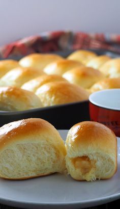 two rolls sitting on a plate next to a pan with some dipping sauces in it