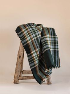 a green and black plaid blanket sitting on top of a wooden stool