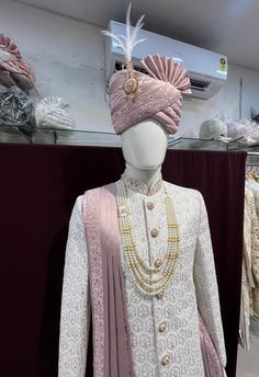 a mannequin dressed in a white and pink outfit with pearls on it's head