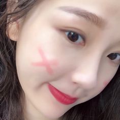 a close up of a person with a red cross painted on her face and eyebrows