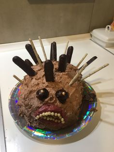 a chocolate cake with sticks sticking out of it's face on a counter top