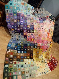 a very large quilt on the floor with many different colors and shapes in it's center