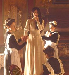 three women dressed in period clothing standing near each other and one woman holding her hand up to her mouth