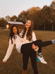 two young women are posing for the camera in an open field with their arms around each other