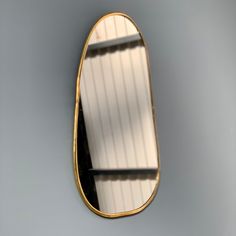 an oval mirror hanging on the wall in front of a gray wall with white and black stripes