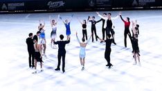 a group of people standing on top of a snow covered ice skating rink with their arms in the air