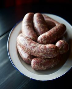 several sausages in a white bowl on a table