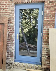 a blue door with a reflection of a pine tree in it